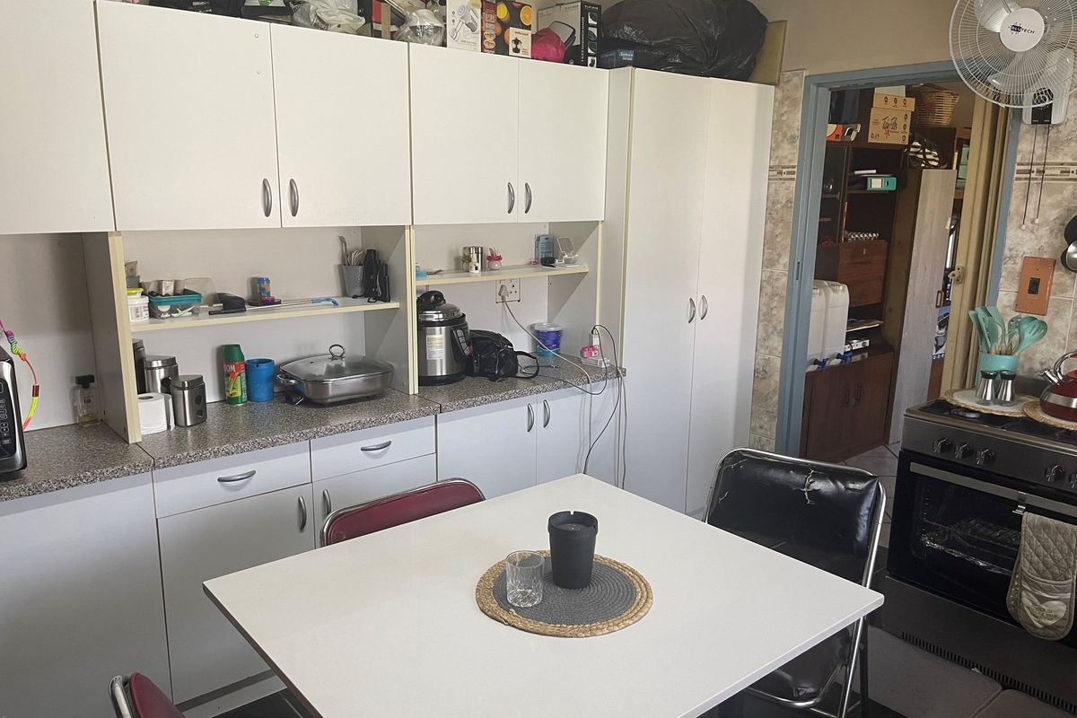 Functional kitchen featuring white cabinetry, laminate countertops, and a built-in oven, providing a practical workspace with adjacent storage area.