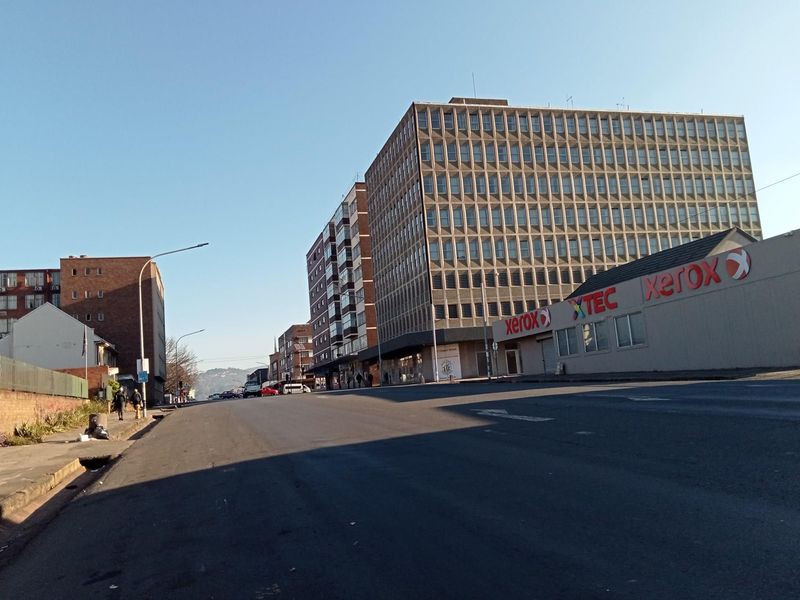 A street-level view showing the surrounding urban environment, including nearby commercial buildings and infrastructure along the road.