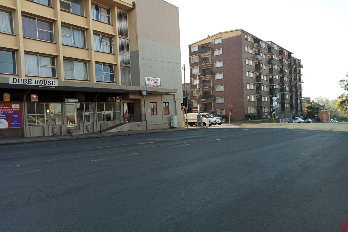 Street-level view of Dube House apartment building and surrounding urban infrastructure.