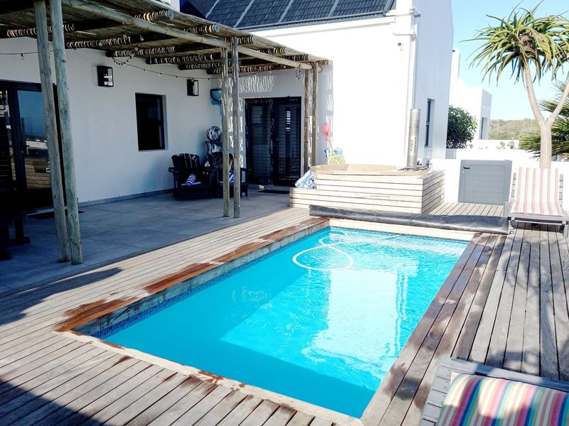 Outdoor entertainment area featuring a swimming pool, timber decking, and a covered patio with a wooden pergola structure.