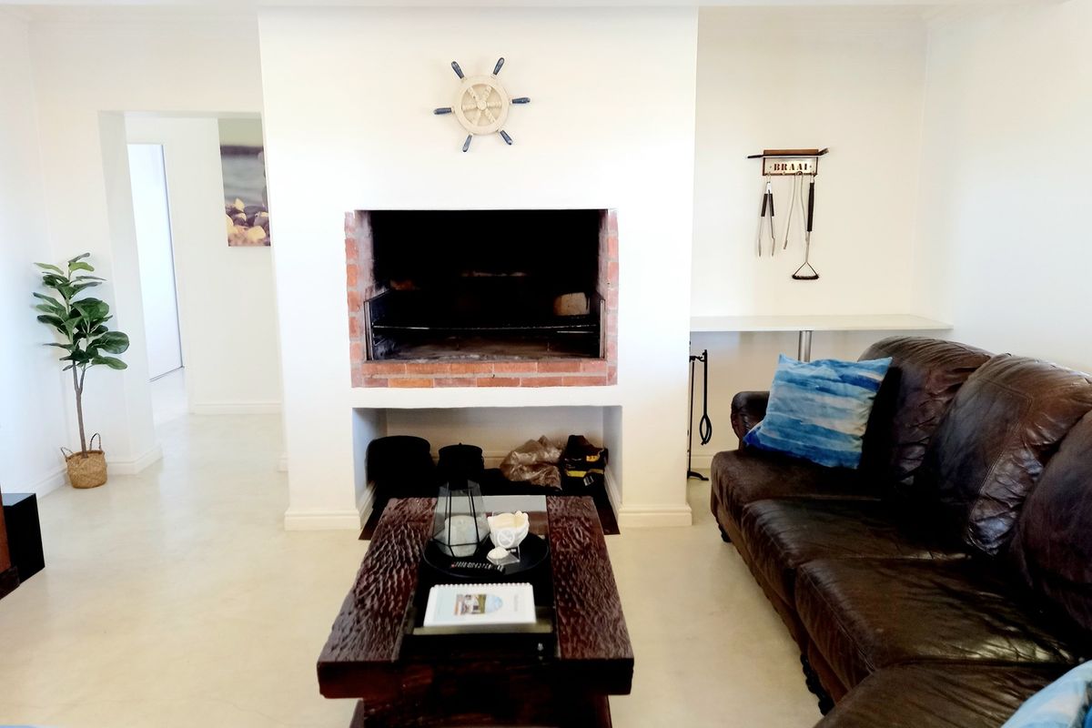 A living area featuring a built-in brick fireplace and hearth, finished with neutral flooring and clean white walls.