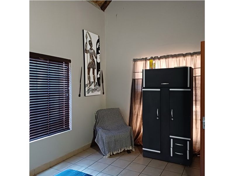 A bedroom featuring tiled flooring and venetian blinds, offering a functional space with neutral wall finishes.