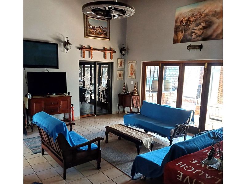Spacious living room featuring high vaulted ceilings, tiled flooring, and large sliding glass doors that provide ample natural light and access to the outdoors.