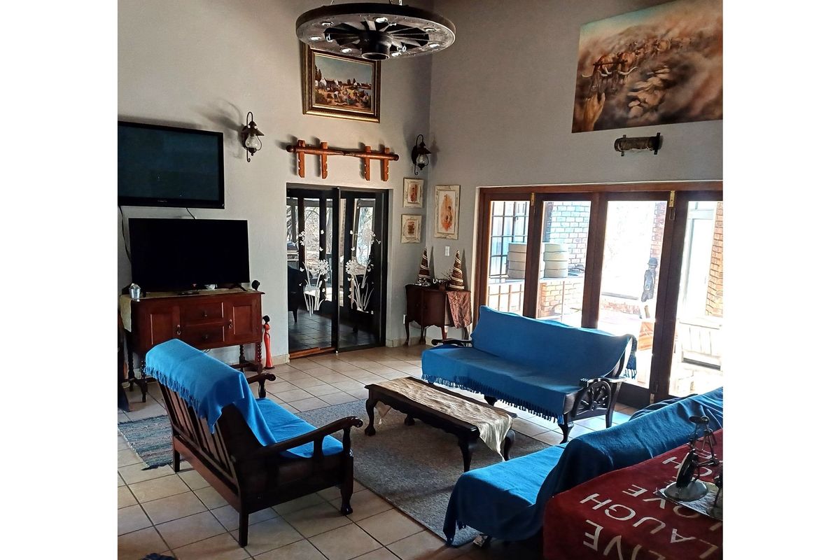 Spacious living room featuring high vaulted ceilings, tiled flooring, and large sliding glass doors that provide ample natural light and access to the outdoors.