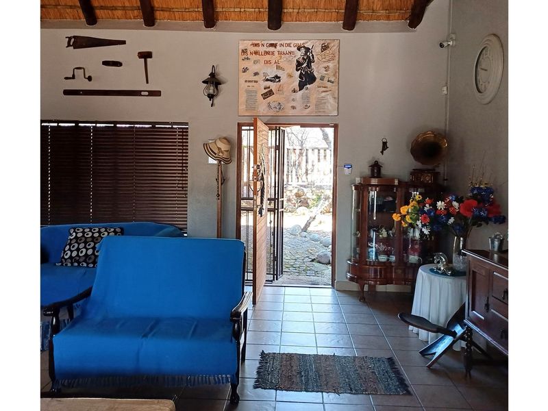 Entrance area featuring tiled flooring, exposed timber rafters with a thatched ceiling, and direct access to the exterior through a security gate.