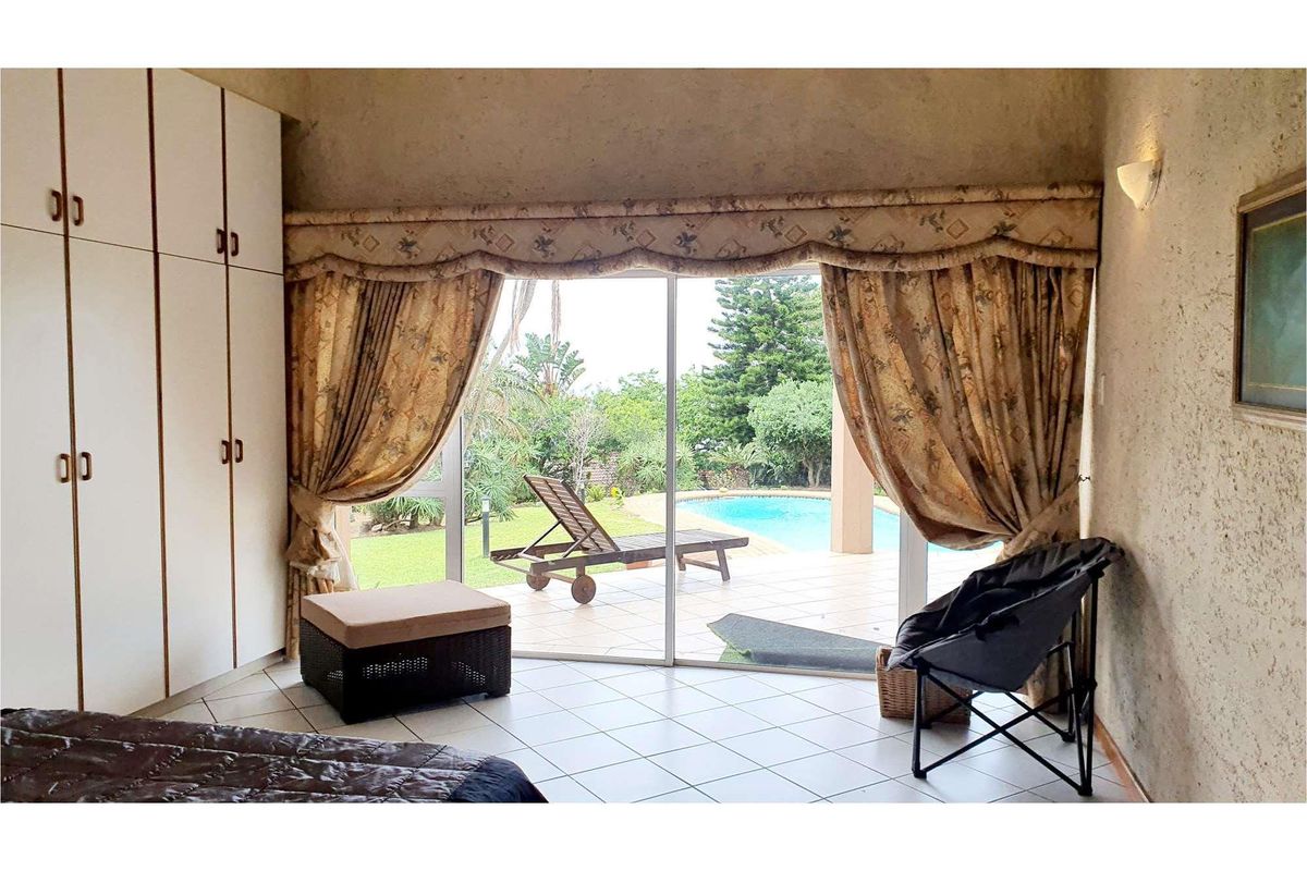 Bedroom featuring built-in cupboards, tiled flooring, and sliding glass doors providing direct access to the patio and swimming pool area.