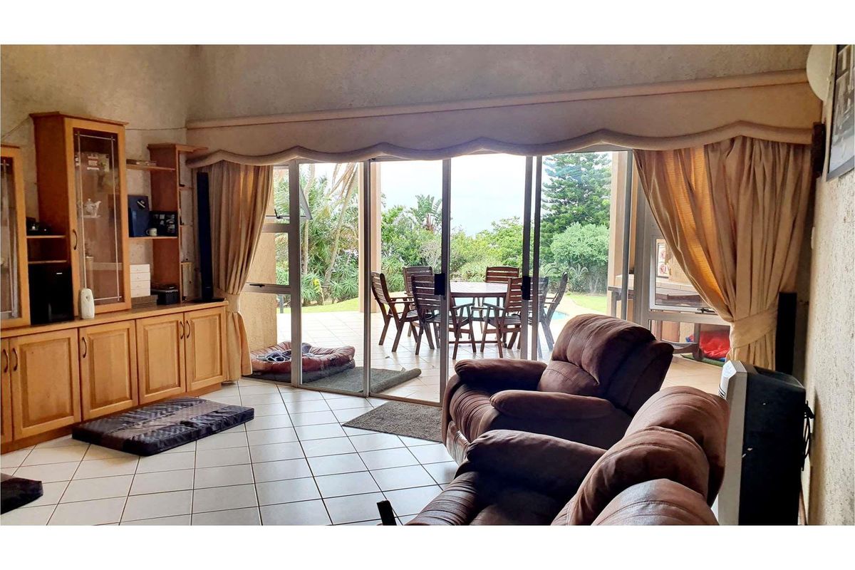 Spacious living room featuring tiled flooring and large sliding glass doors that provide seamless access to the outdoor patio and garden area.