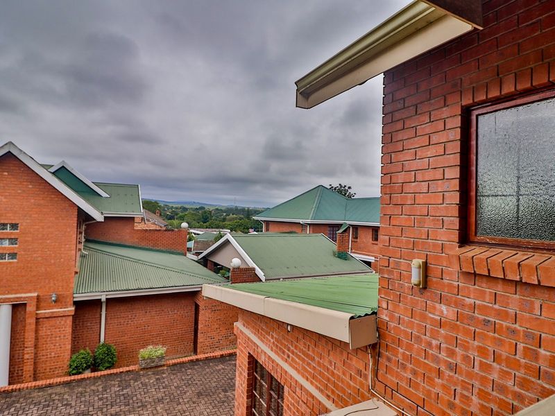 Elevated view overlooking the surrounding residential estate, featuring face brick architecture and green corrugated metal roofing.