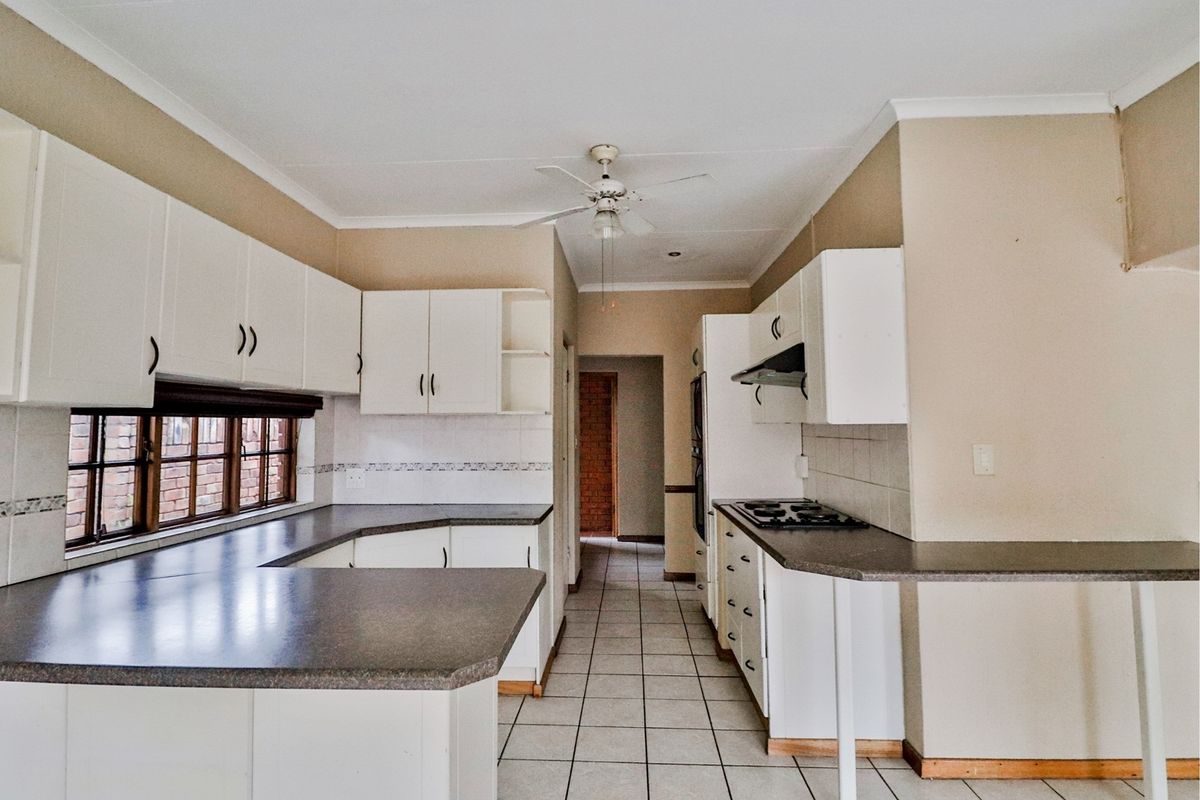 A functional kitchen featuring white cabinetry, laminate countertops, tiled flooring, and a built-in hob with an extractor fan.