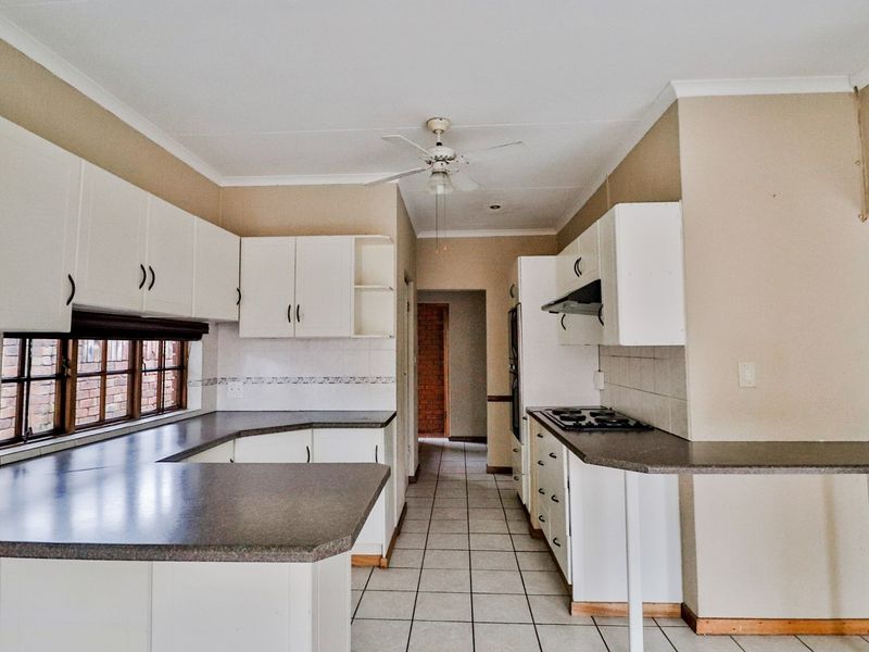 A functional kitchen featuring white cabinetry, laminate countertops, tiled flooring, and a built-in hob with an extractor fan.