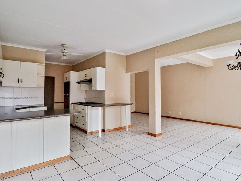 Open-plan kitchen and living area featuring tiled flooring, built-in cabinetry with laminate countertops, a gas hob, and an integrated extractor fan.