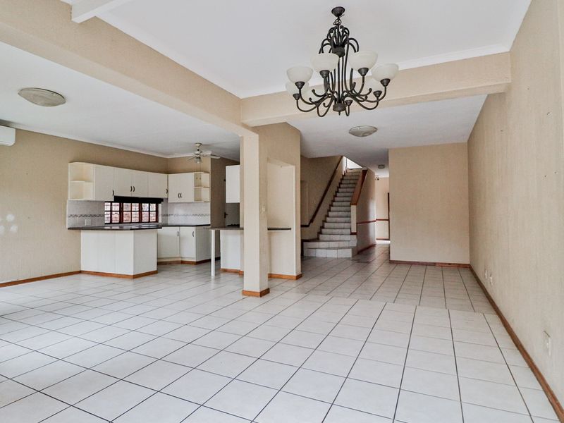 Spacious open-plan living and kitchen area featuring tiled flooring, built-in cabinetry, and a staircase leading to the upper level.