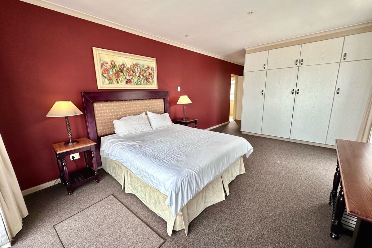 Spacious bedroom featuring built-in wardrobes, carpeted flooring, and a bold accent wall.