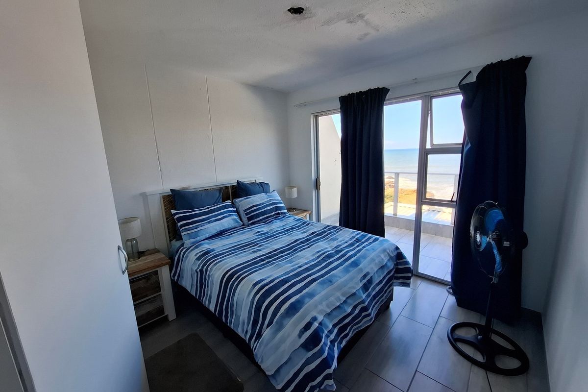 Bedroom featuring tiled flooring and sliding glass doors that open onto a balcony with ocean views.