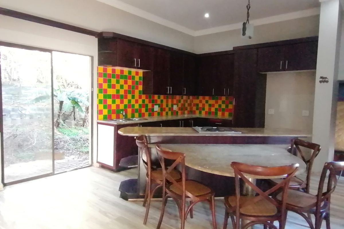 Kitchen featuring dark wood cabinetry, stone countertops, a built-in hob, and a vibrant multi-colored tile backsplash with direct access to the garden.