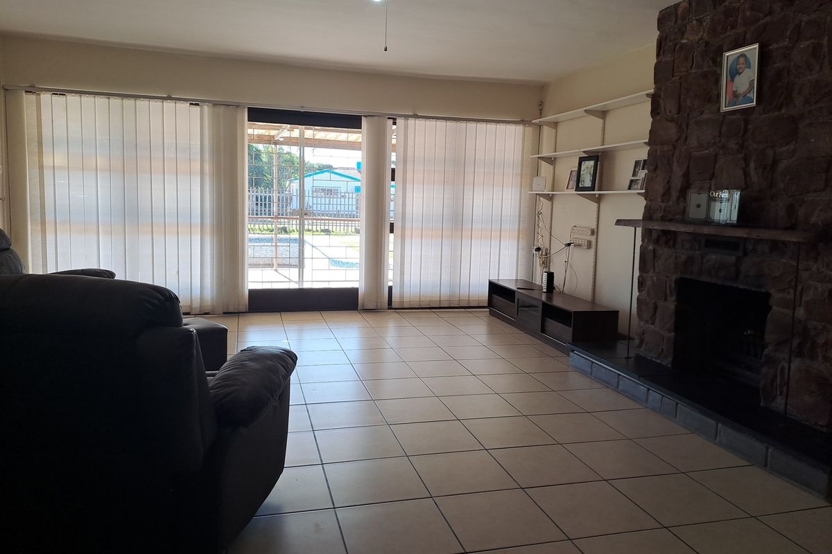 Spacious living room featuring a prominent stone fireplace, tiled flooring, and large sliding glass doors providing access to the outdoor area.