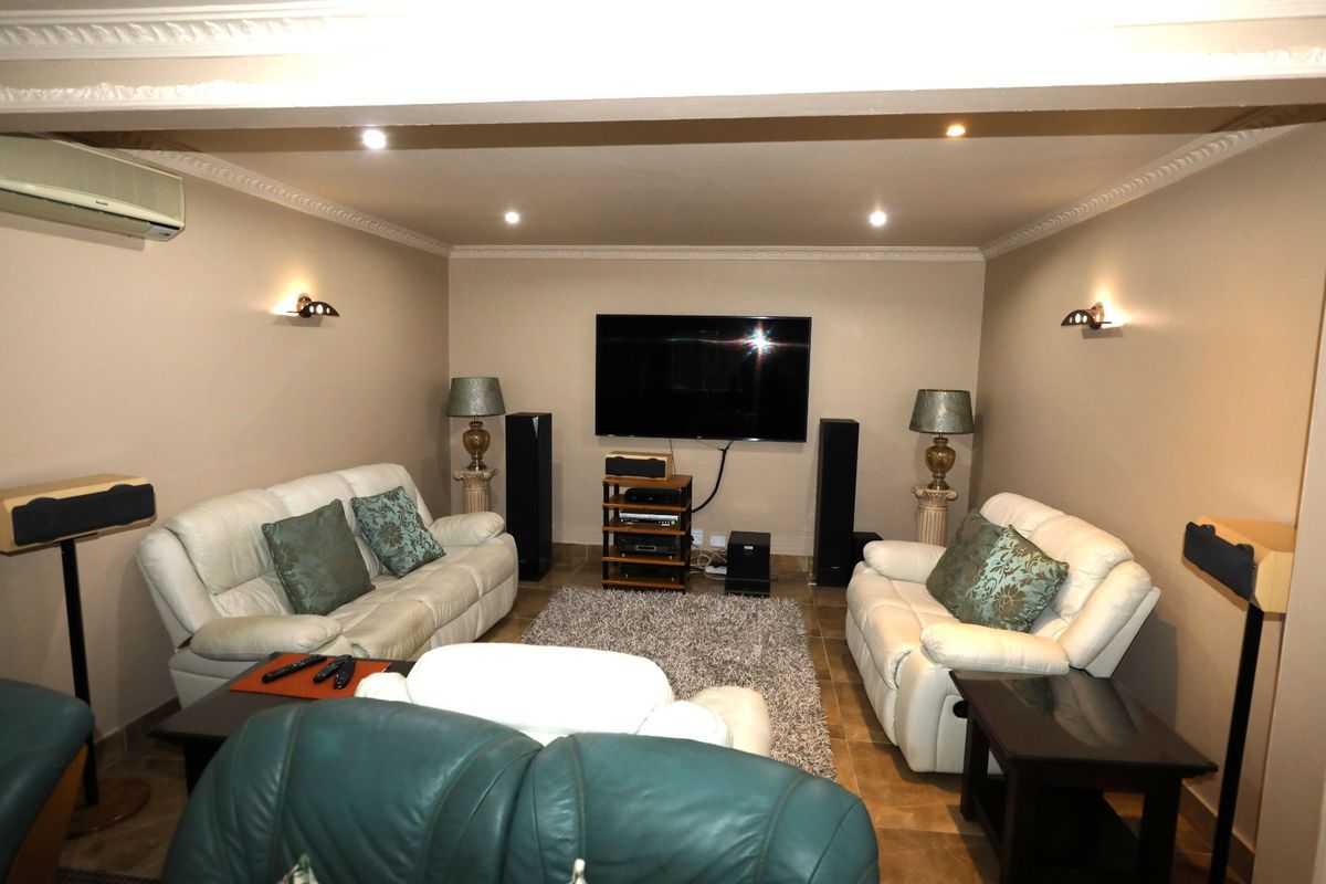 A comfortable living room featuring tiled flooring, decorative crown molding, recessed lighting, and wall-mounted air conditioning.