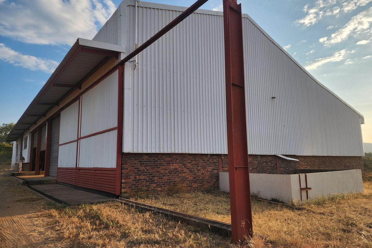 Large industrial-style farm shed featuring corrugated metal cladding, brick base, and exposed steel structural supports.
