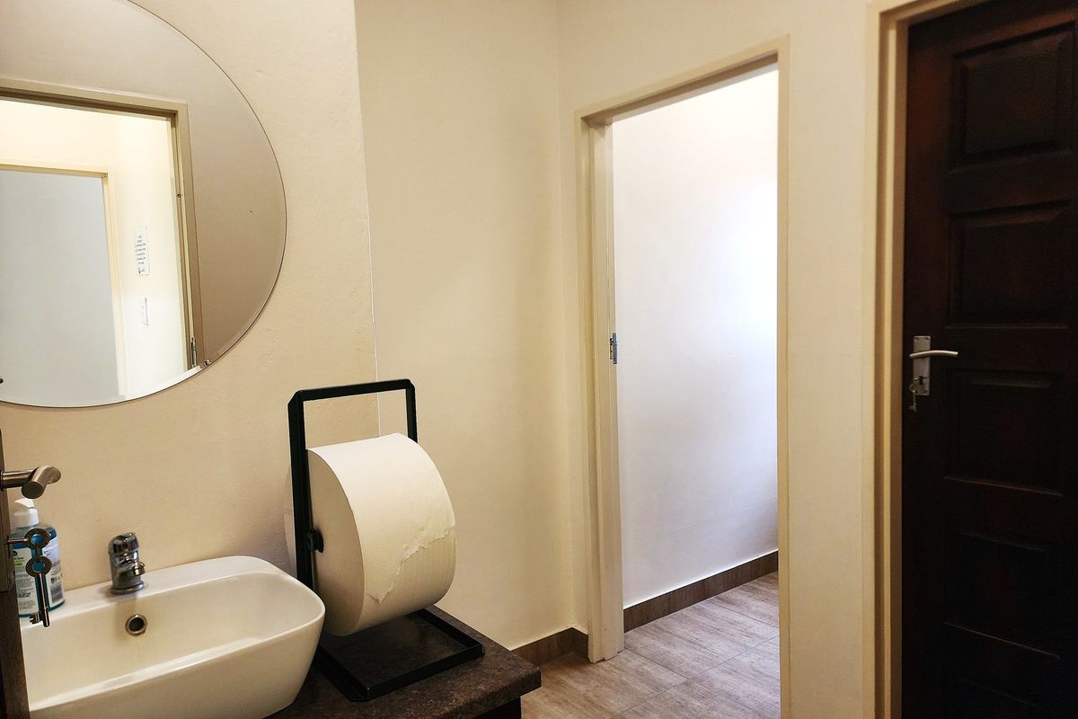 A functional bathroom featuring a modern vessel sink, wall-mounted circular mirror, and tiled flooring, providing a clean and practical space.