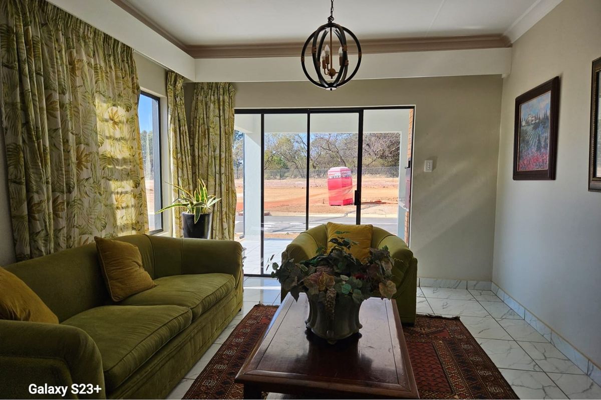 A bright living room featuring tiled flooring, decorative crown molding, and large sliding glass doors that provide direct access to the outdoor patio area.