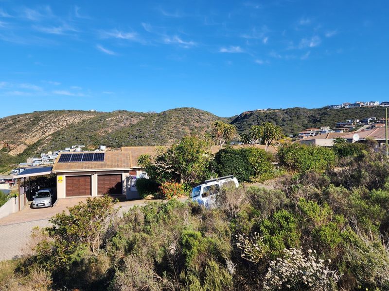Elevated view of a residential property featuring a double garage with solar panels, set against a scenic hillside landscape.