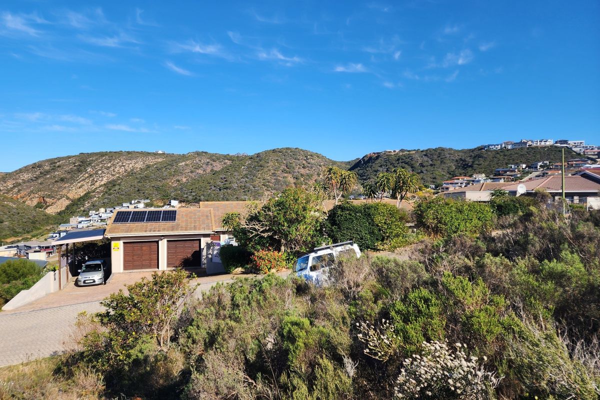 Elevated view of a residential property featuring a double garage with solar panels, set against a scenic hillside landscape.