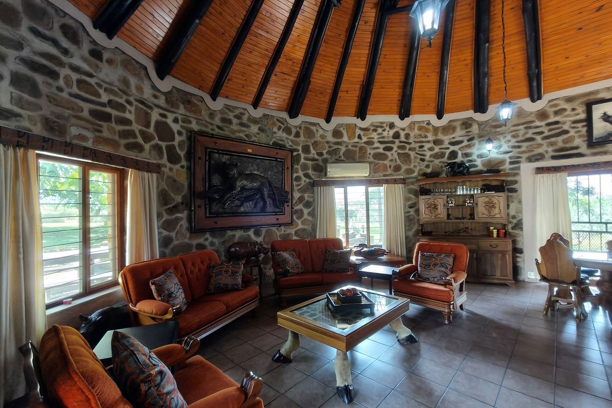 Spacious living room featuring a high vaulted timber ceiling, rustic stone walls, and tiled flooring, creating a warm and unique architectural atmosphere.