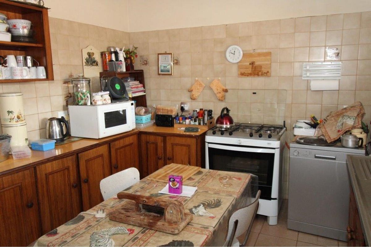 A functional kitchen featuring wooden cabinetry, tiled splashbacks, and a freestanding gas stove, offering a traditional layout with ample counter space.