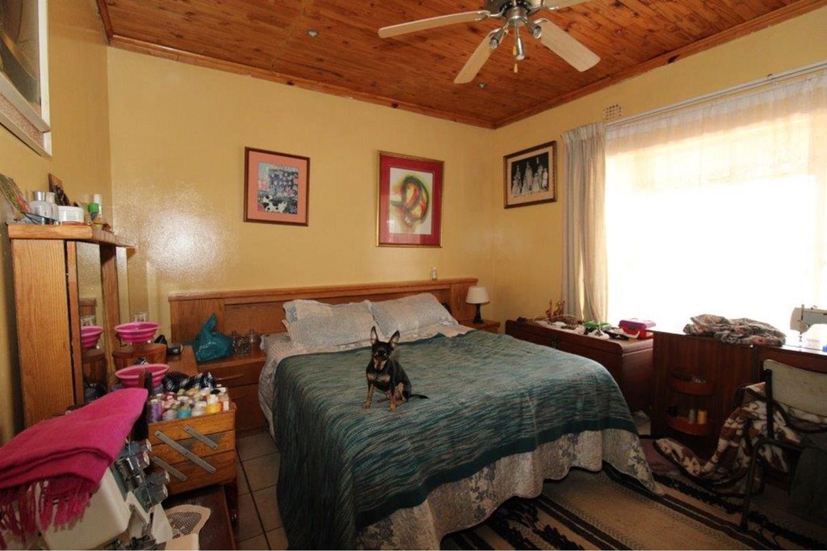A bedroom featuring a wooden ceiling, tiled flooring, and a built-in headboard with integrated bedside tables.