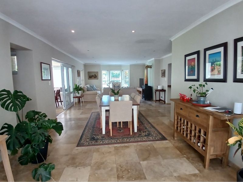 Spacious open-plan living and dining area featuring large format stone floor tiles, recessed downlighting, and a built-in fireplace.
