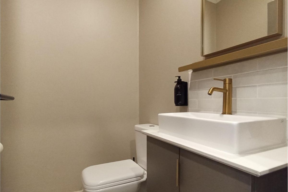 Modern bathroom featuring a sleek vanity with a vessel sink, brass-finish faucet, subway tile backsplash, and a wall-mounted mirror.