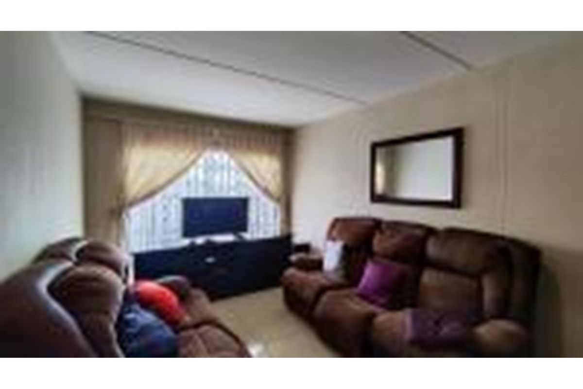 A comfortable living room featuring tiled flooring and a large window that allows for natural light.