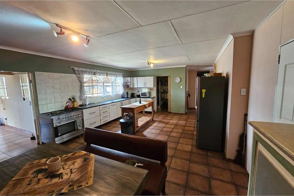 Spacious kitchen featuring tiled flooring, built-in cabinetry, a gas stove, and an adjoining pantry area, offering a functional layout with potential for modernization.