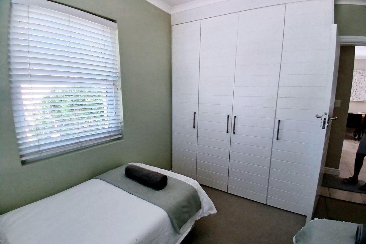 A bedroom featuring built-in white cabinetry with horizontal detailing and venetian blinds on the window.