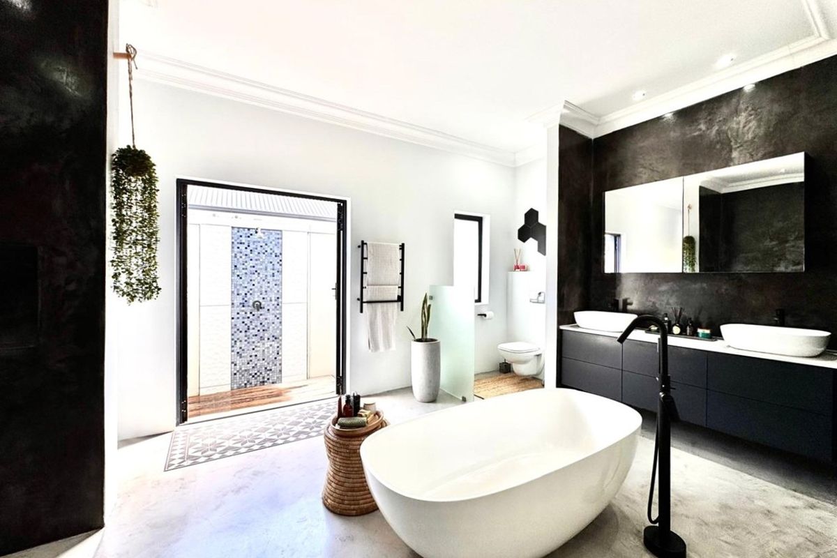 Modern bathroom featuring a freestanding bathtub, double vanity with vessel sinks, and a seamless transition to an outdoor shower area.