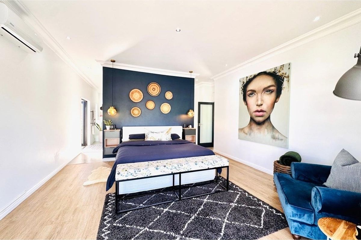 Spacious bedroom featuring a dark blue accent wall, recessed ceiling lighting, and a wall-mounted air conditioning unit.
