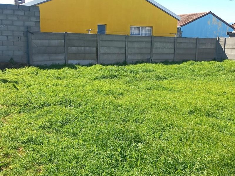 A spacious rear garden area featuring a large lawn enclosed by concrete boundary walls, offering potential for landscaping and outdoor development.