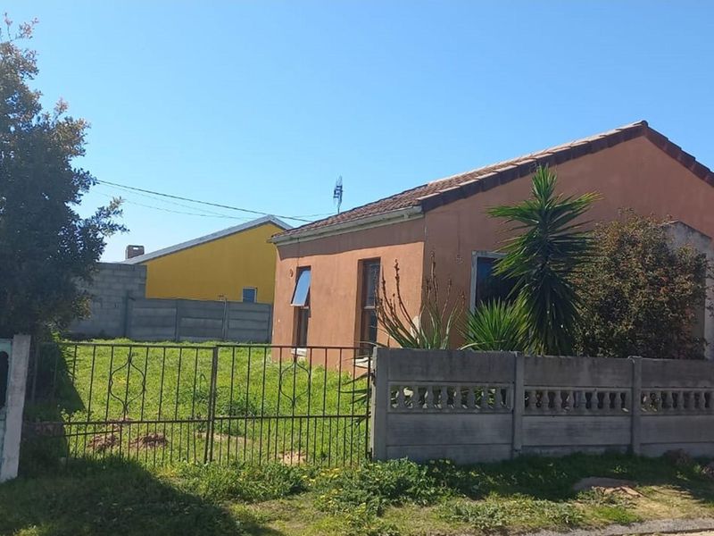 Exterior view of a single-story residential property featuring a terracotta-colored facade, tiled roof, and a fenced front yard area.