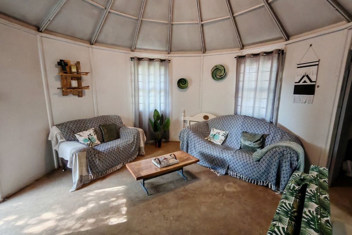 A circular living area featuring a unique domed ceiling structure, concrete flooring, and natural light through multiple windows.