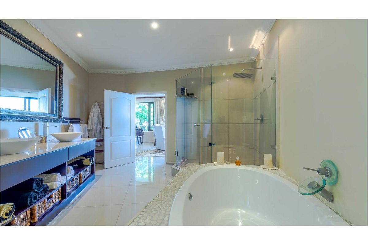 Modern bathroom featuring a double vanity with vessel sinks, a glass-enclosed walk-in shower with a rain head, and a built-in bathtub with tiled surround.