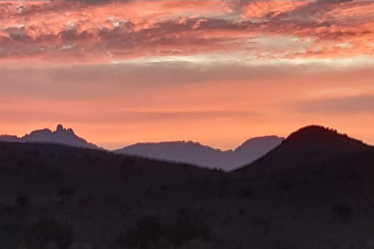 A scenic view of the surrounding mountain landscape at sunset, showcasing the natural beauty and horizon of the vacant land.