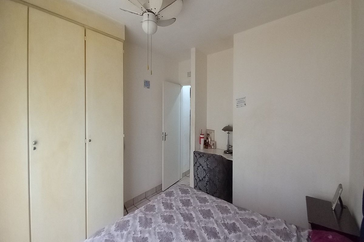 A bedroom featuring built-in wardrobes and a ceiling fan, offering a functional layout with neutral finishes.