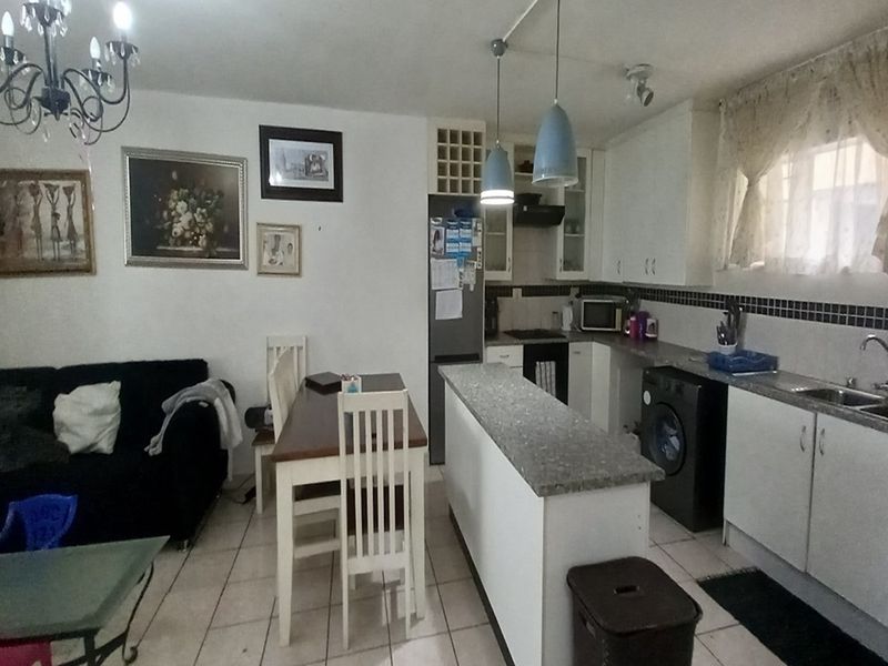 Open-plan kitchen and living area featuring a breakfast bar, built-in cabinetry, and tiled flooring in a functional apartment layout.