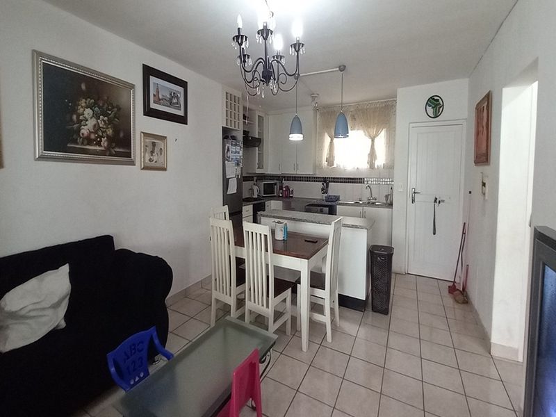 Open plan living and kitchen area featuring tiled flooring, built-in kitchen cabinetry, and a breakfast counter.