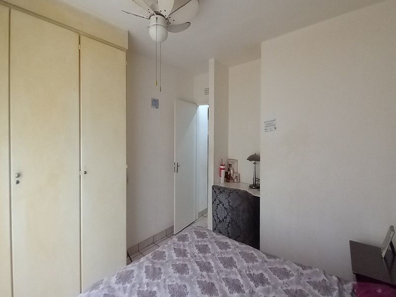 A bedroom featuring built-in wardrobes and a ceiling fan, offering a functional layout with neutral finishes.