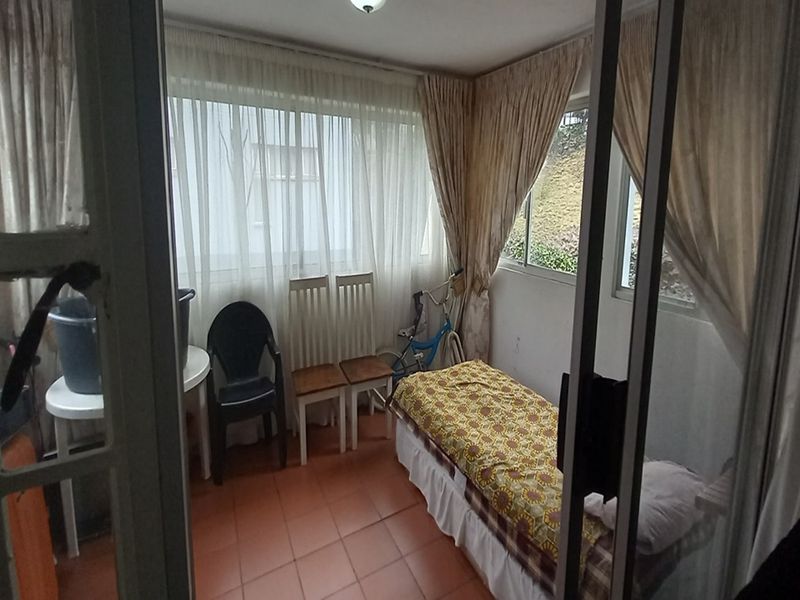 A sunroom or enclosed balcony area featuring tiled flooring and large windows, providing a bright and versatile space for relaxation or storage.