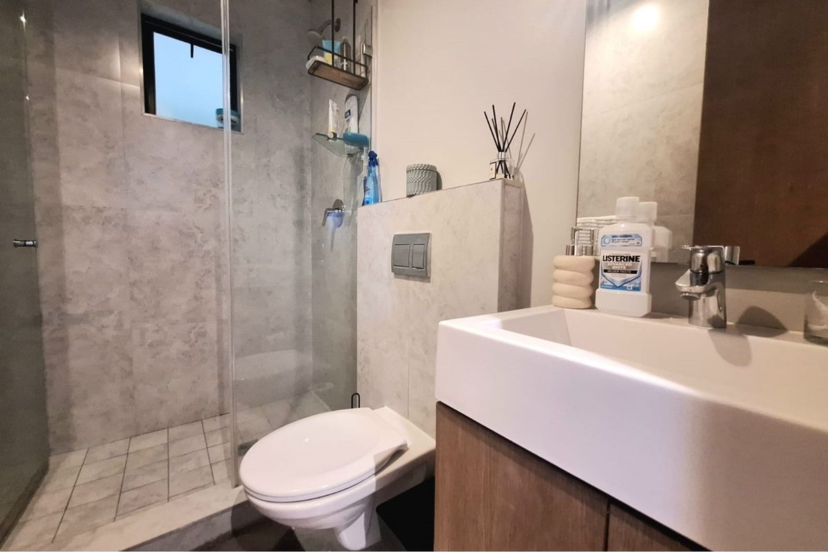 Modern bathroom featuring a walk-in glass shower, wall-mounted toilet, and a contemporary vanity with a basin.