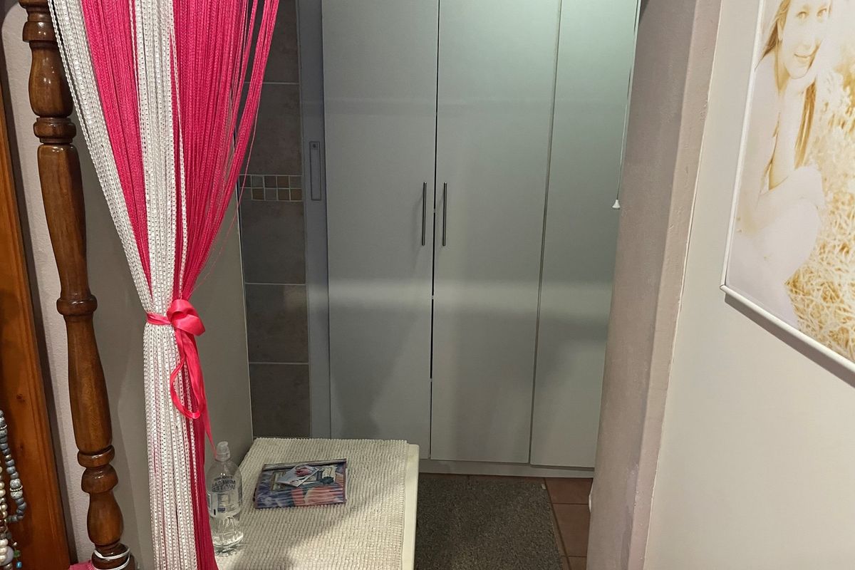 A view of a bedroom area featuring built-in white cabinetry with modern handles and tiled flooring.