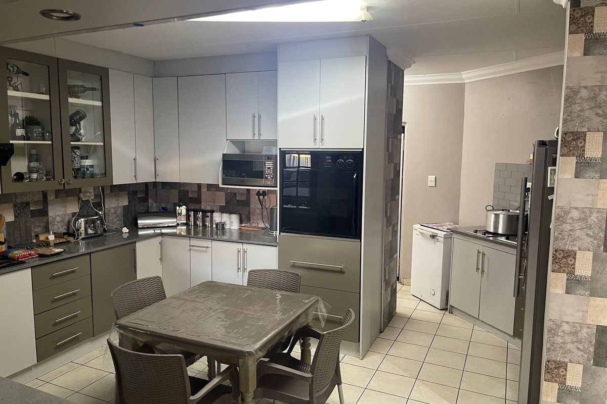 A functional kitchen featuring two-tone cabinetry, built-in oven, microwave, and tiled flooring, offering a practical layout for daily meal preparation.