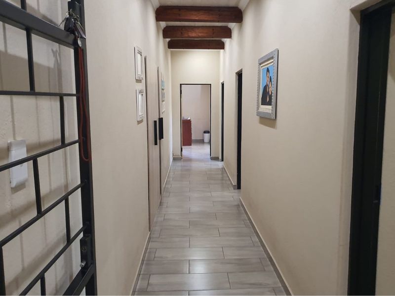 A well-maintained interior hallway featuring exposed timber ceiling beams and modern tiled flooring, providing access to multiple rooms within the property.